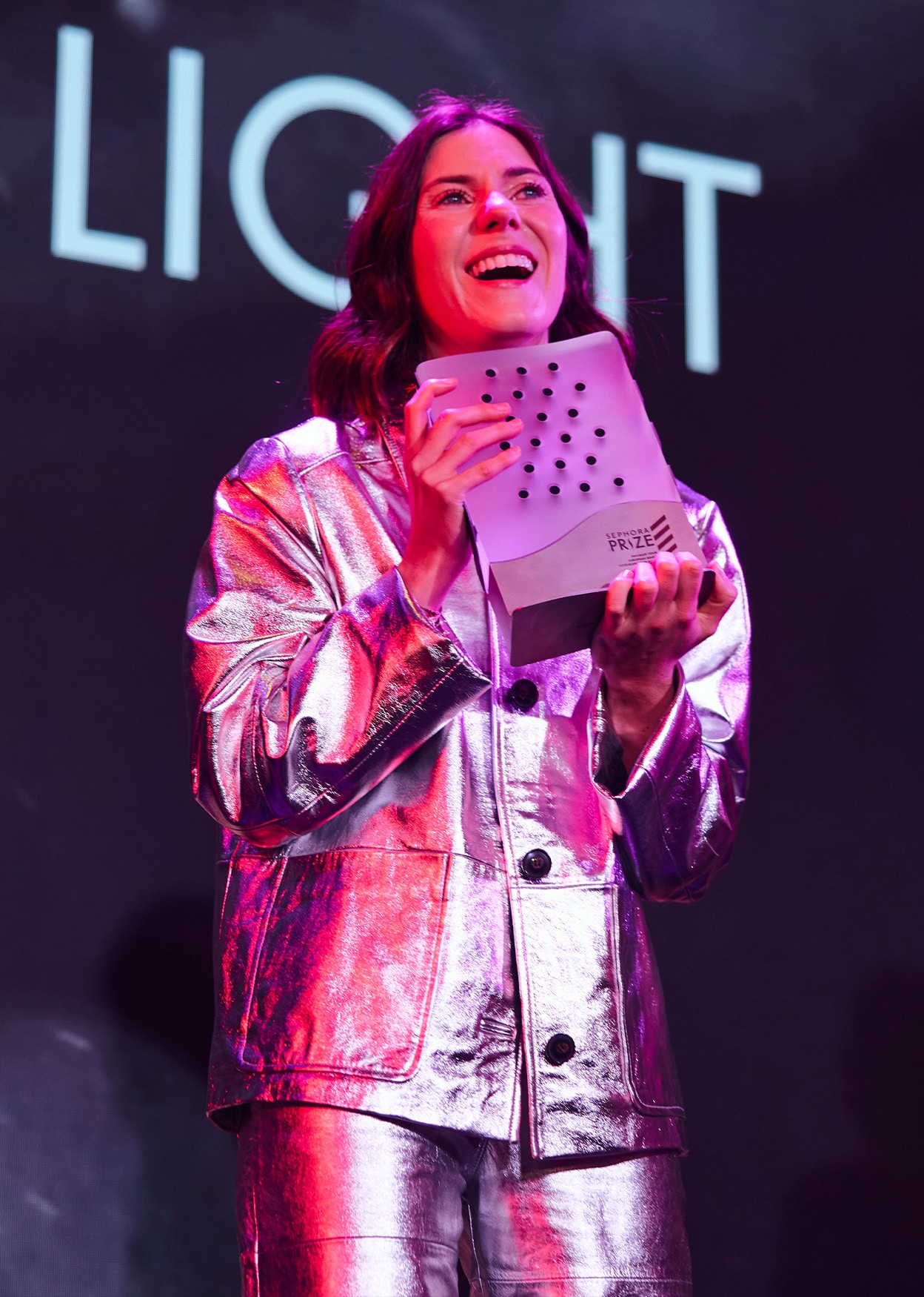 The Substance Of Light winner holding the Sephora Prize trophy